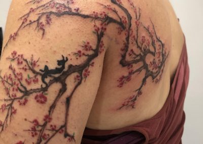 watercolor cherry blossom branch tattoo across shoulder and back by Louise Flowerbloom, Milpitas CA